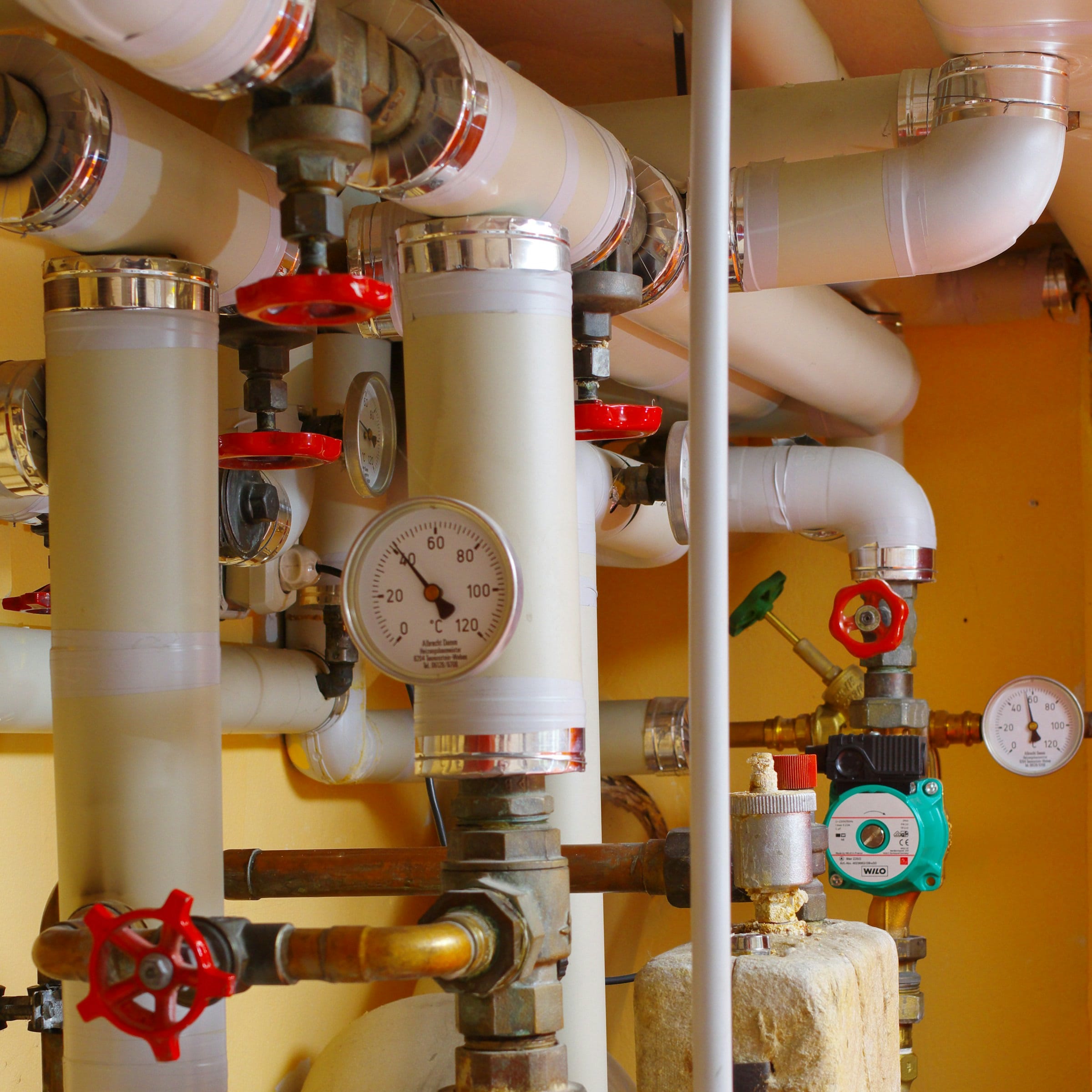 MEP plant room with insulated pipes, pumps, valves, and gauges